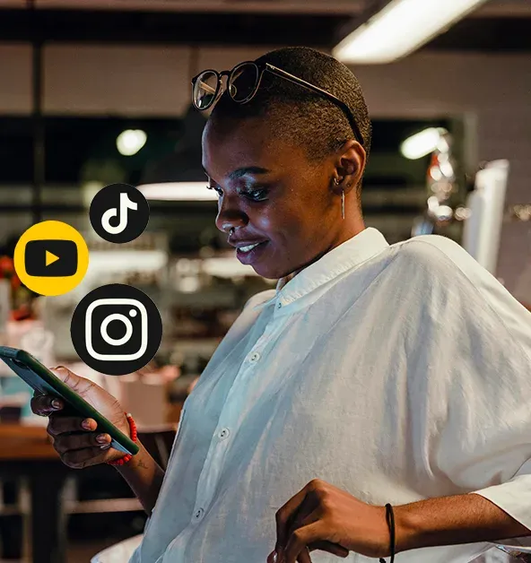 personne consultant son téléphone, entourée des logos YouTube, TikTok et Instagram