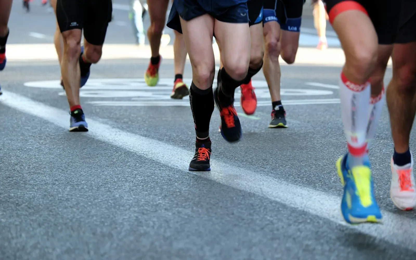 Jambes de coureurs sur une piste, en pleine course.