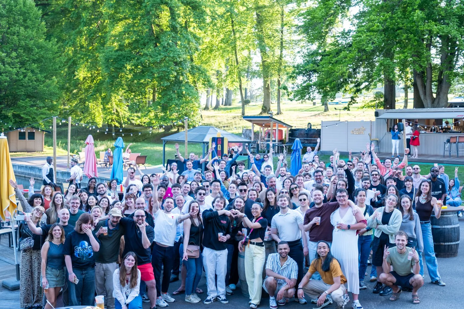 Les équipes Mobsuccess serrées en extérieur sur une terrasse, sous les arbres, bras levés.