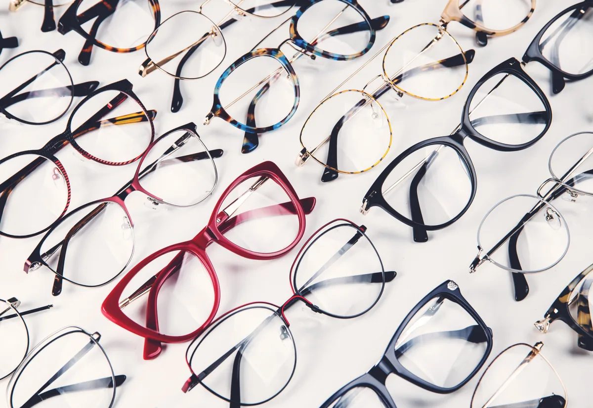 Spectacle frames spread out on a white background, one of them red.